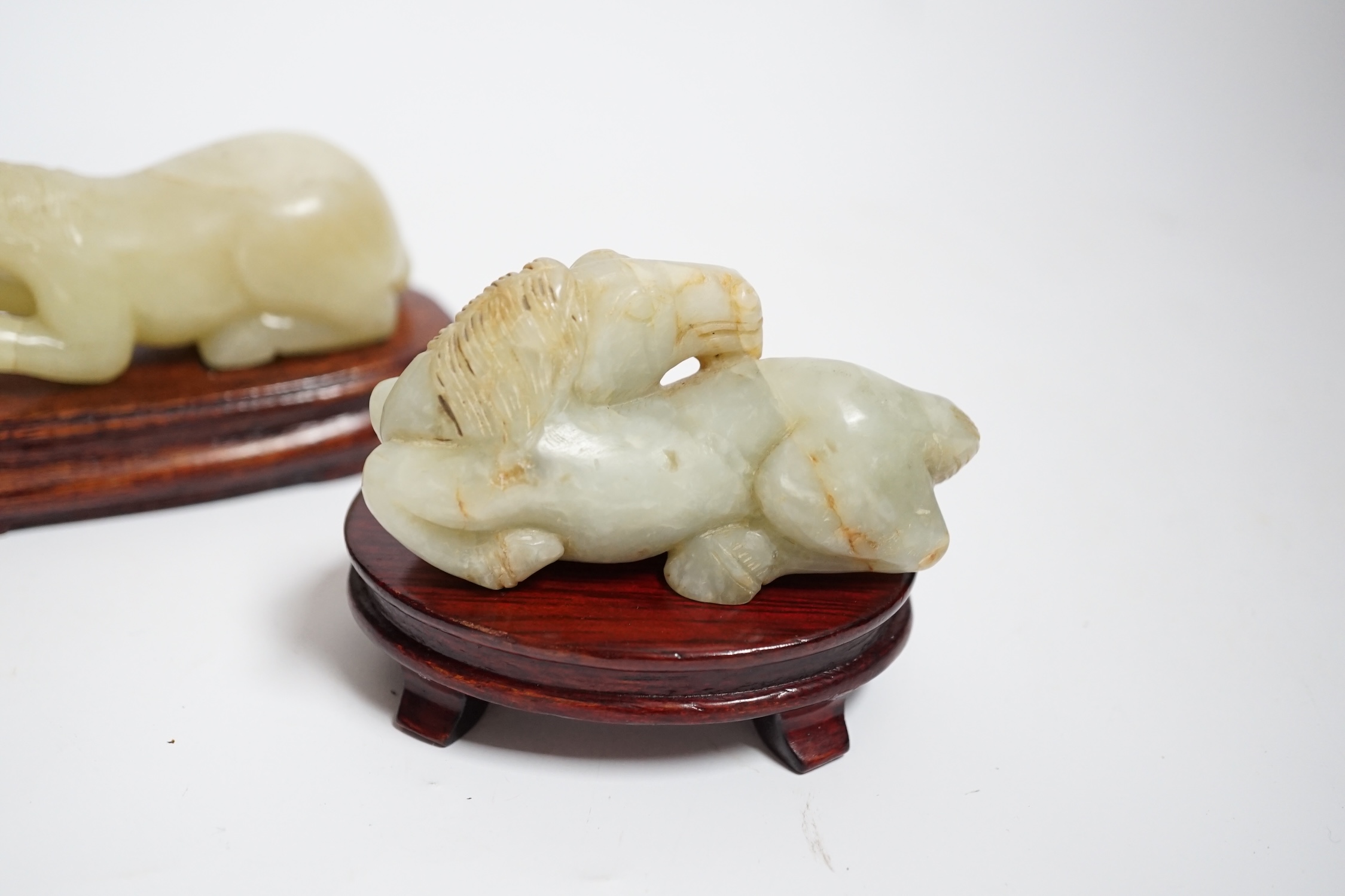 Two Chinese carved jade figures of horses on stands, largest 11cm wide